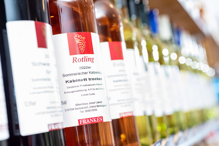 Flaschen mit fränkischem Wein in verschiedenen Sorten in einer Verkaufsreihe.